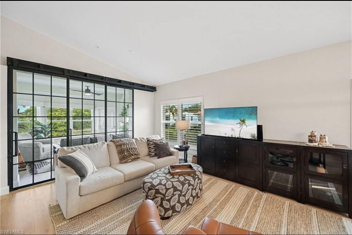 A living room with a couch , chair , coffee table and sliding glass doors.