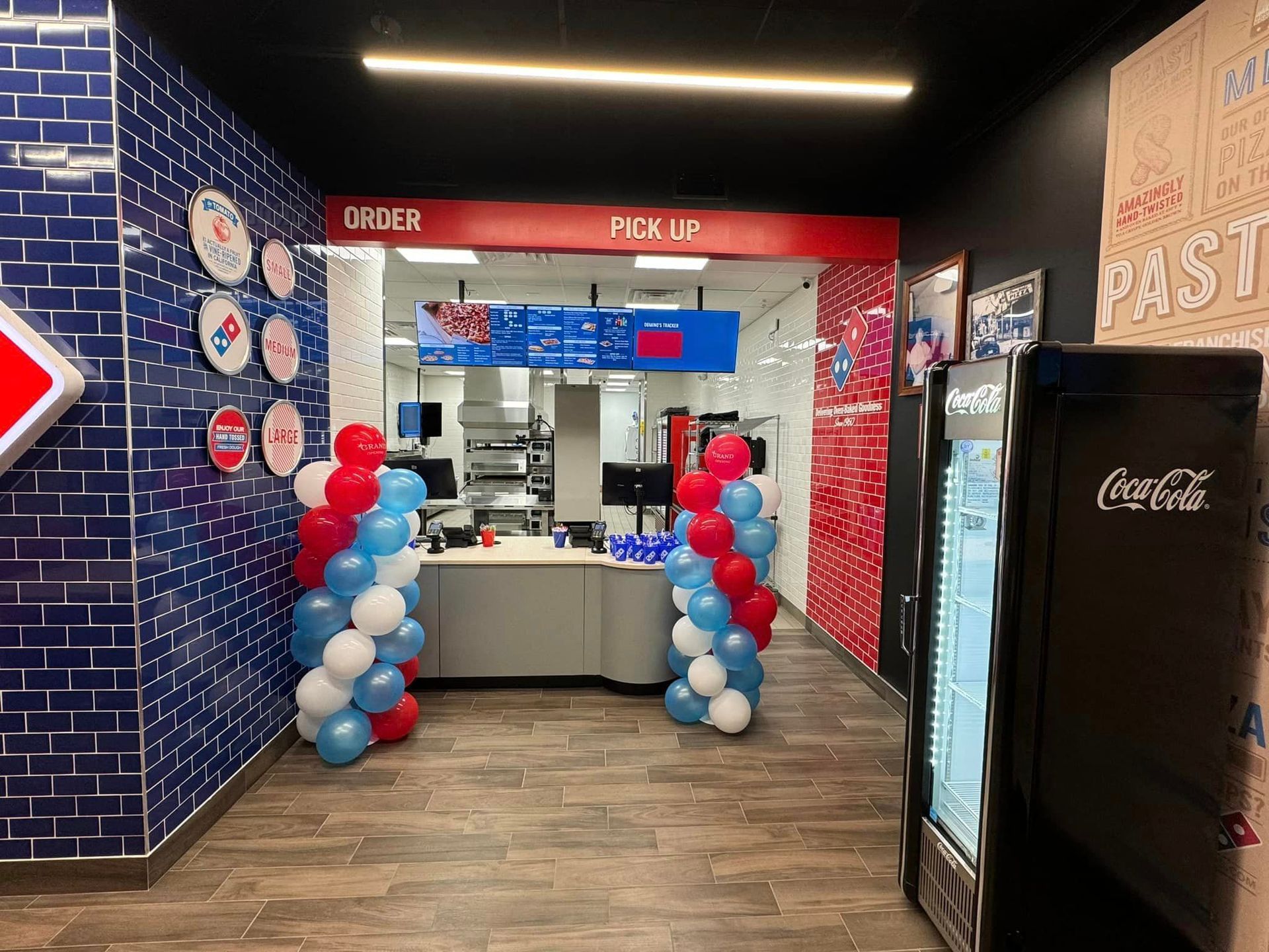 A domino 's pizza restaurant with balloons and a coca cola refrigerator.