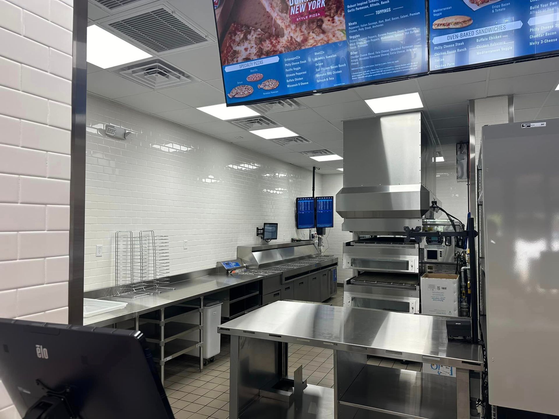 A large kitchen with stainless steel appliances and a pizza oven.