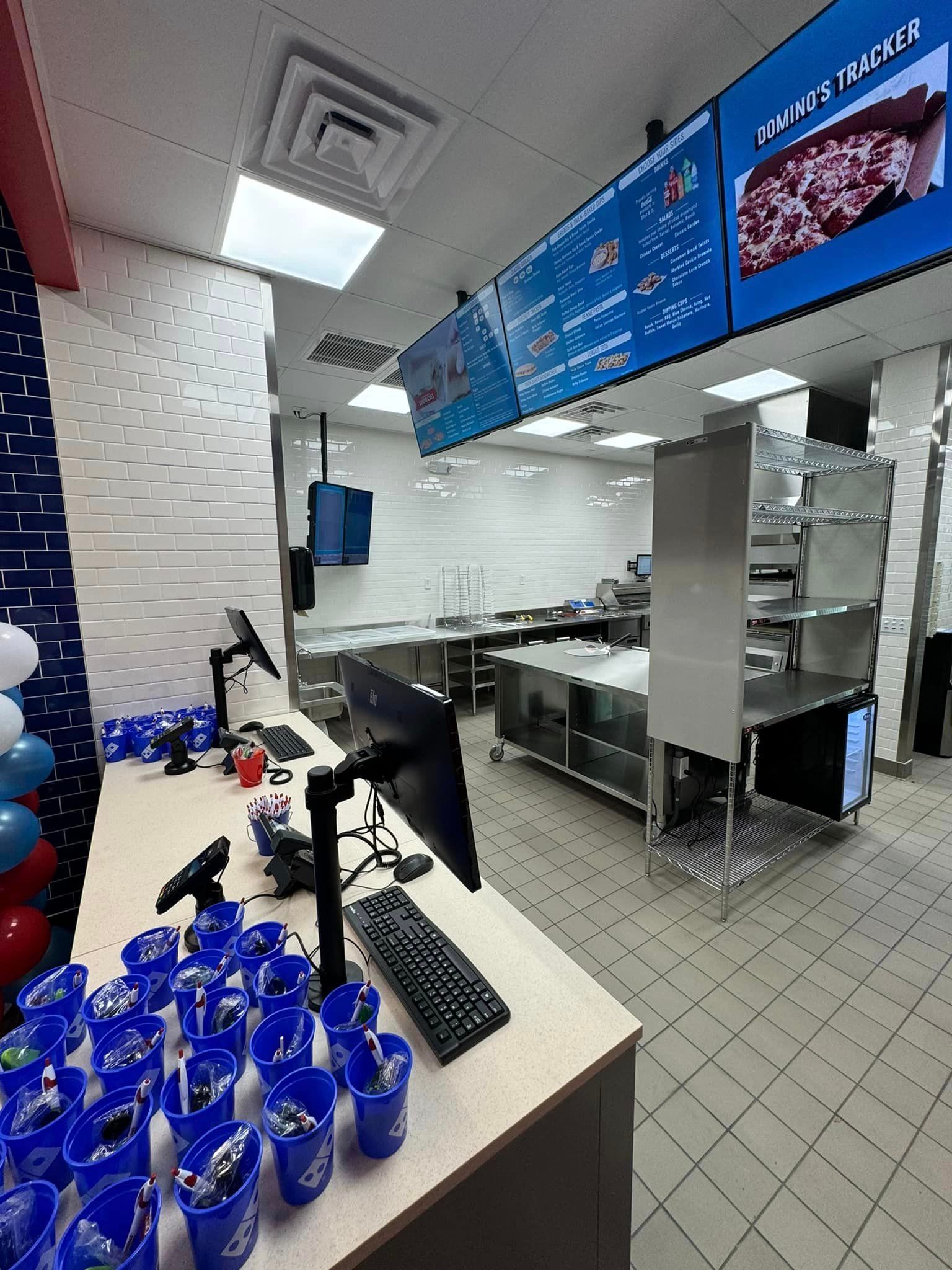 A domino 's pizza restaurant with a lot of blue cups on the counter.