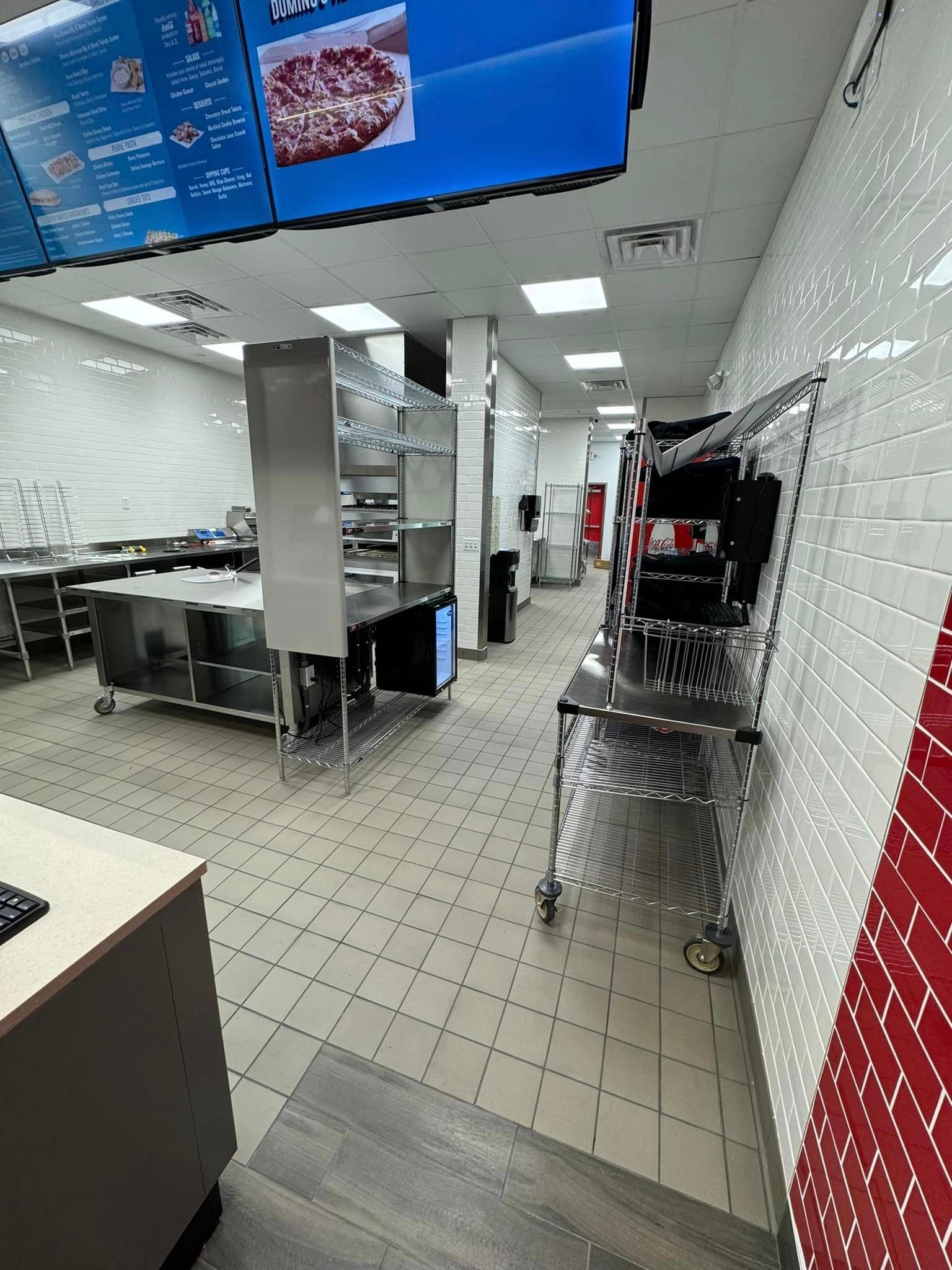 A kitchen with a lot of stainless steel appliances and a large screen on the ceiling.