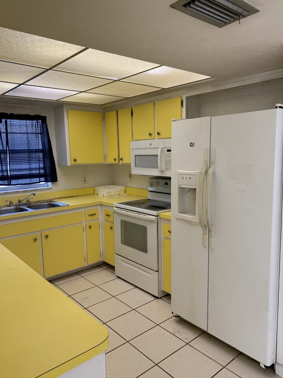 A kitchen with yellow cabinets and a white refrigerator