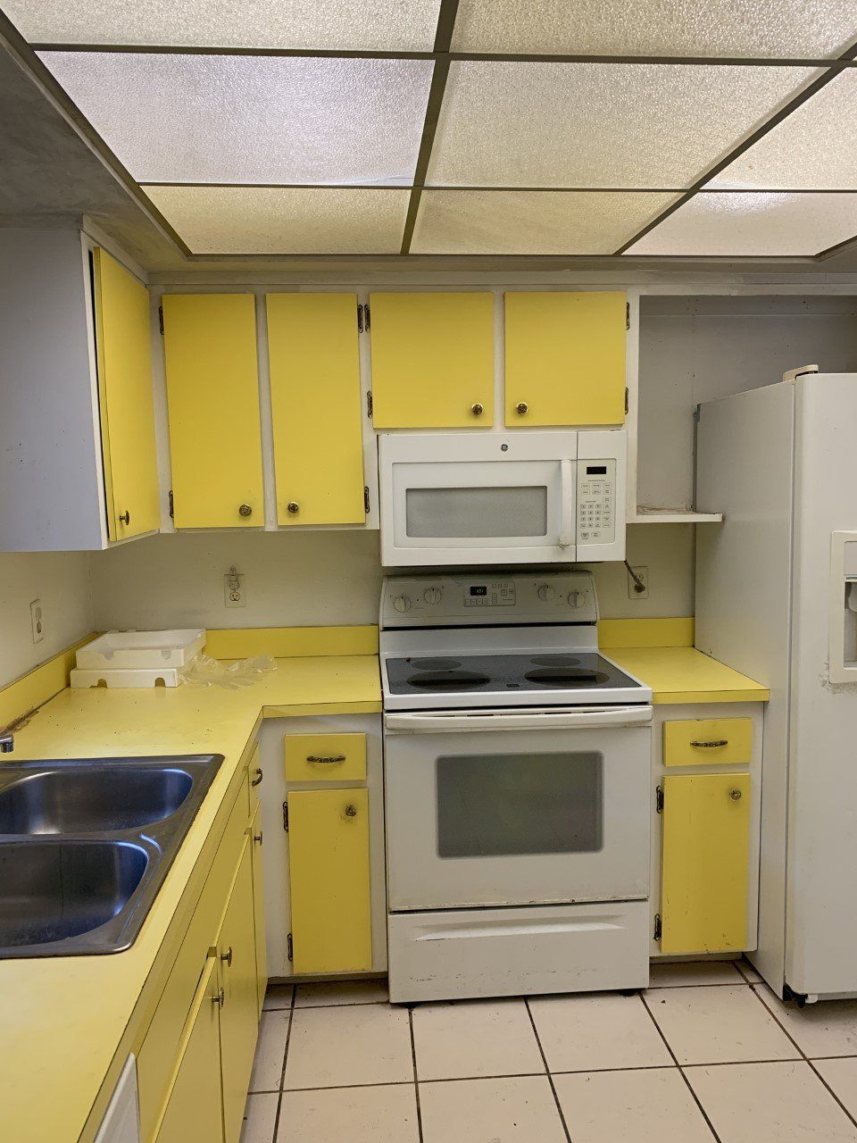 A kitchen with yellow cabinets and white appliances