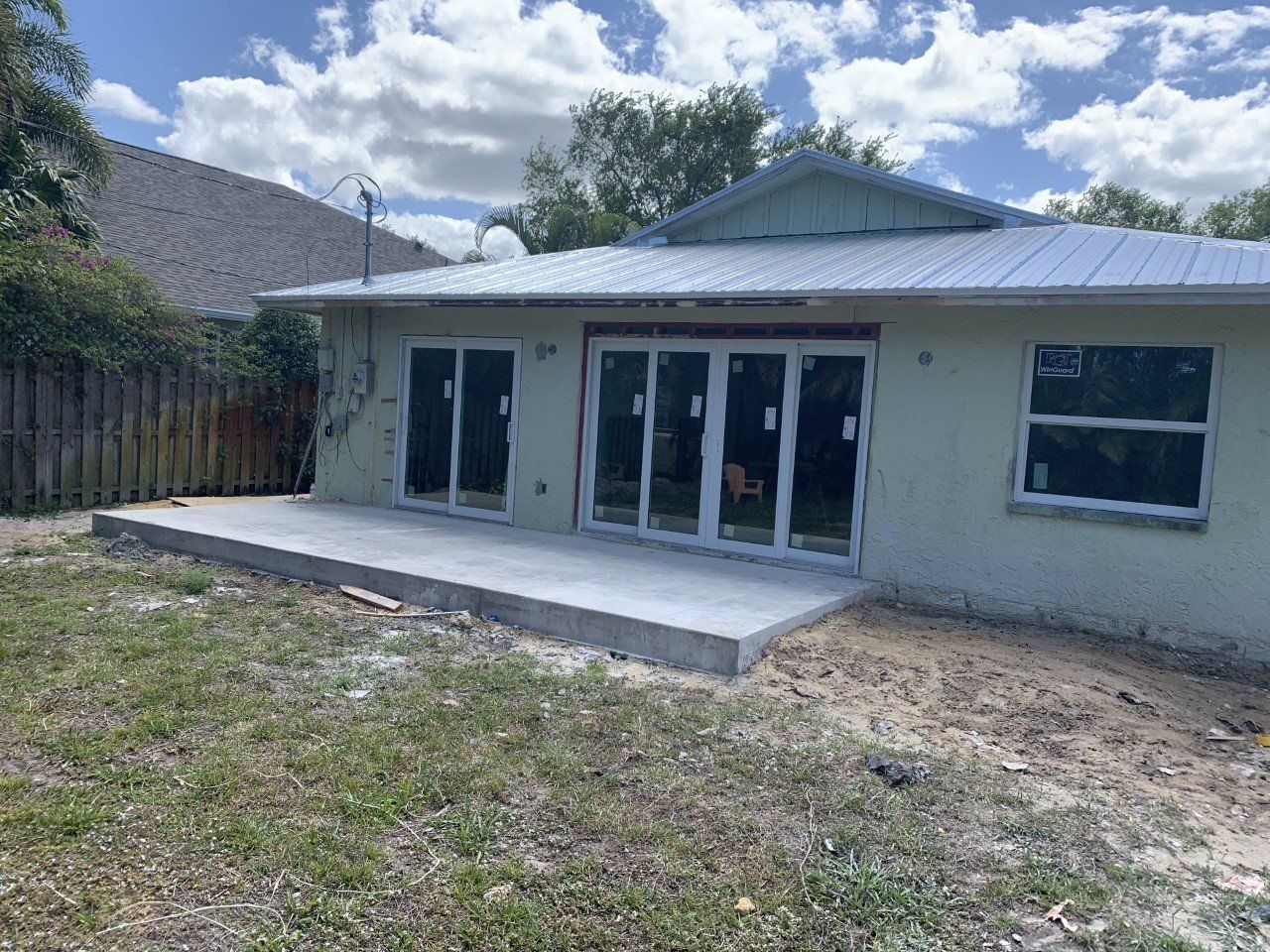 A house with sliding glass doors and a concrete patio in the backyard.