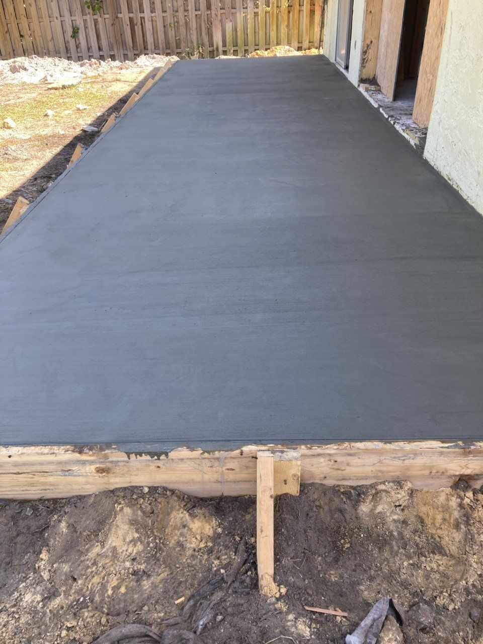 A concrete driveway is being built in front of a house.