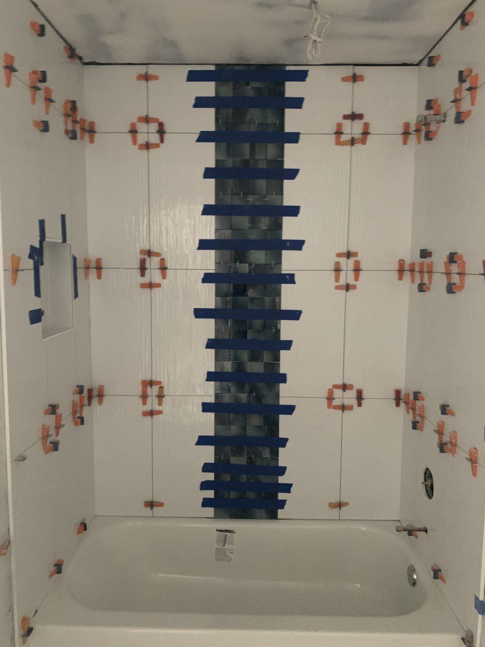A bathtub in a bathroom under construction with tile spacers