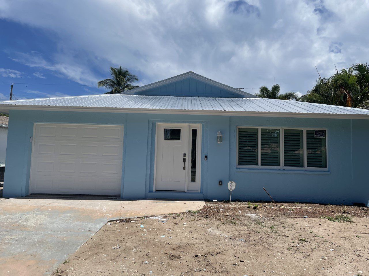 A blue house with a white garage door and a white roof.
