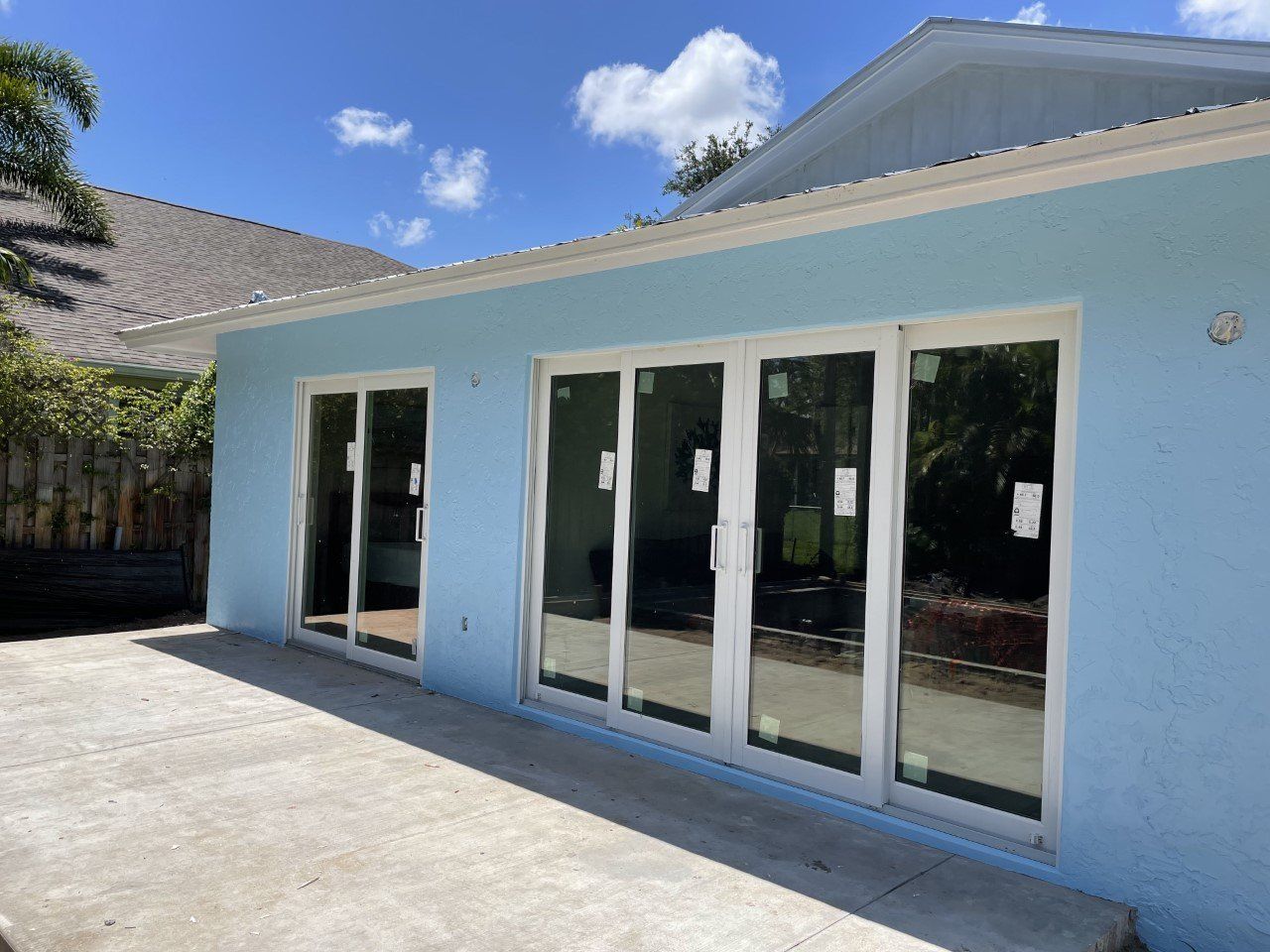 A blue house with white sliding glass doors and a patio.