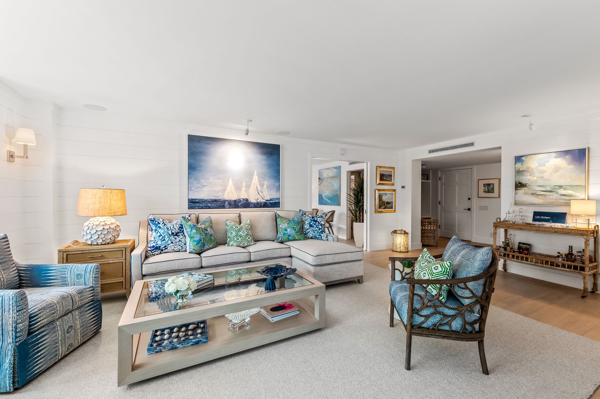 A living room with a couch , chairs , coffee table and paintings on the wall.
