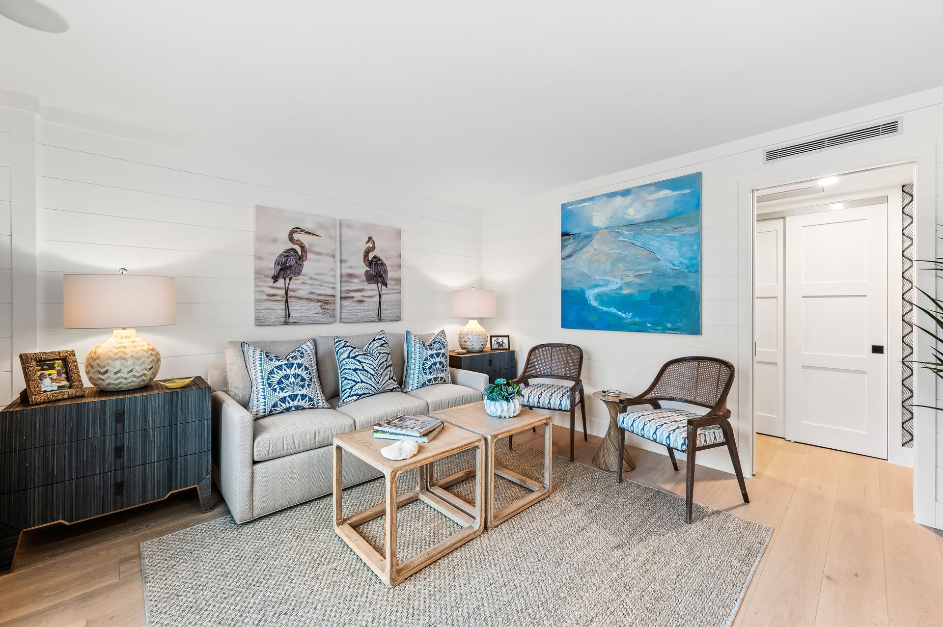 A living room with a couch , chairs , a coffee table and a painting on the wall.