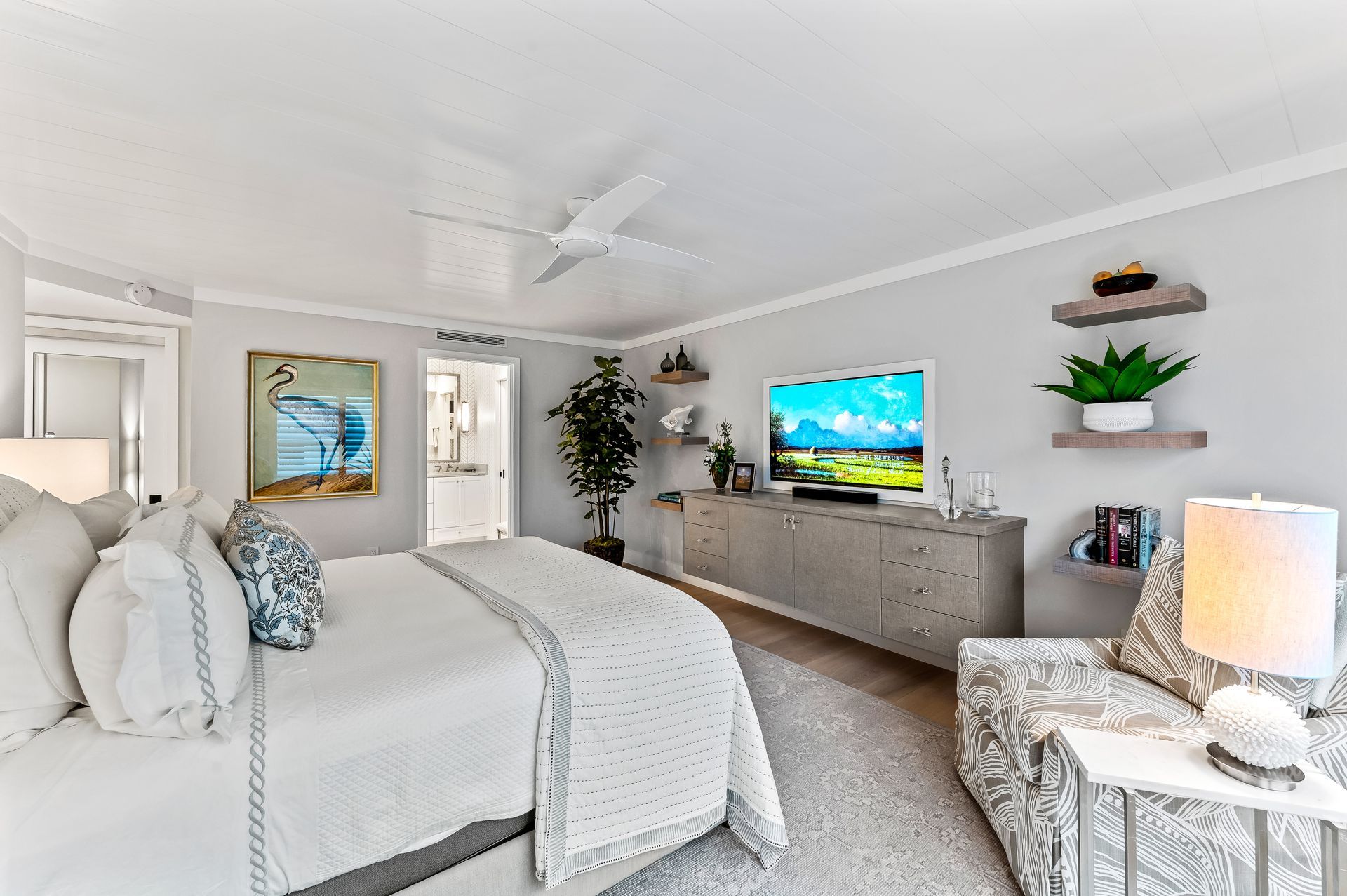 A bedroom with a bed , chair , television and ceiling fan.