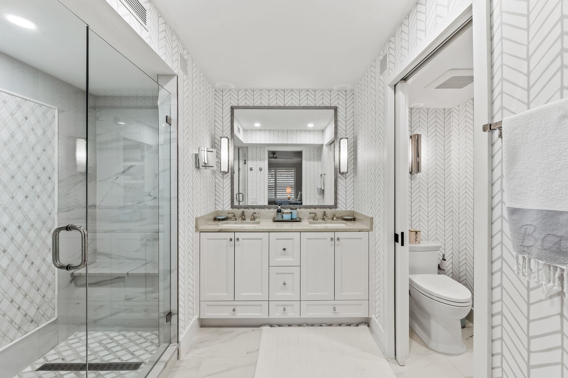 A bathroom with two sinks , a toilet , and a walk in shower.