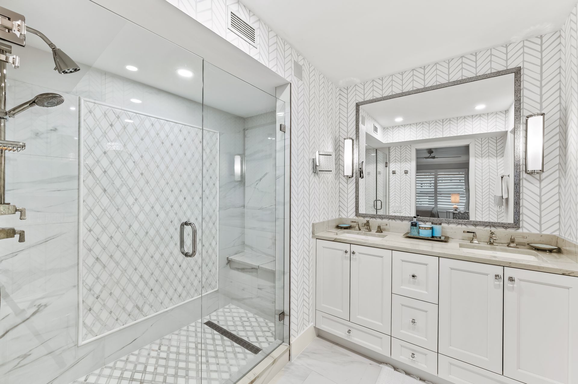 A bathroom with a walk in shower , two sinks , and a large mirror.