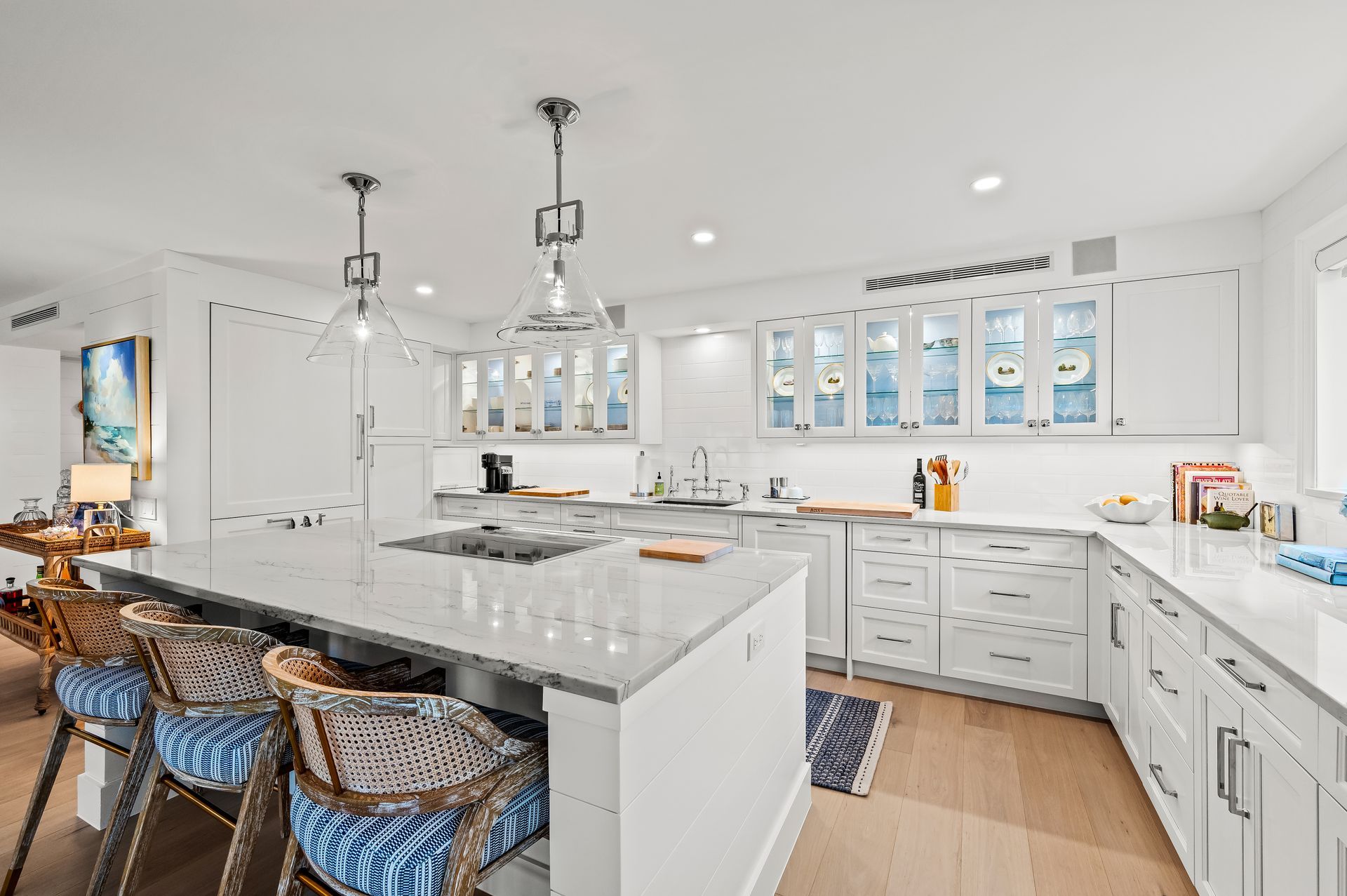 A kitchen with white cabinets , granite counter tops , and a large island.