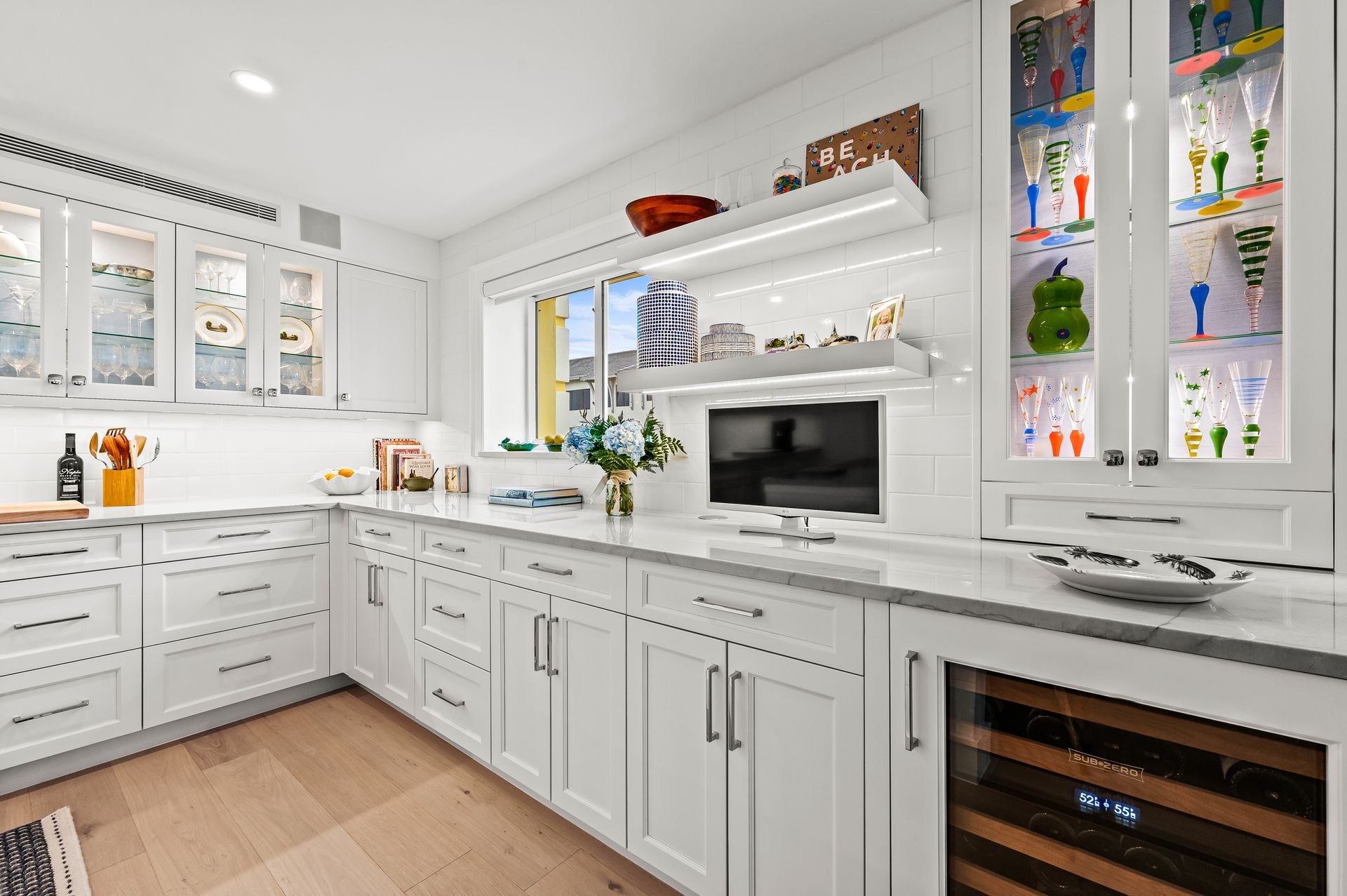 A kitchen with white cabinets and a wine cooler.