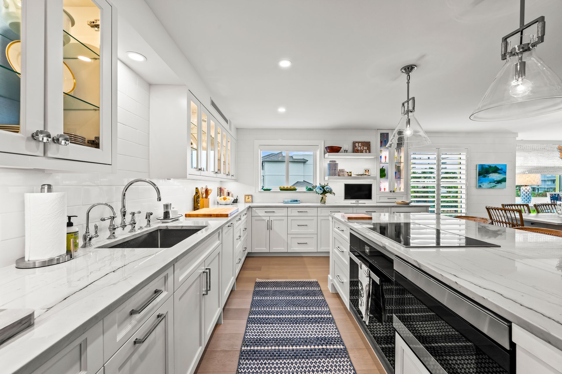A kitchen with white cabinets , stainless steel appliances , a sink , and a rug.