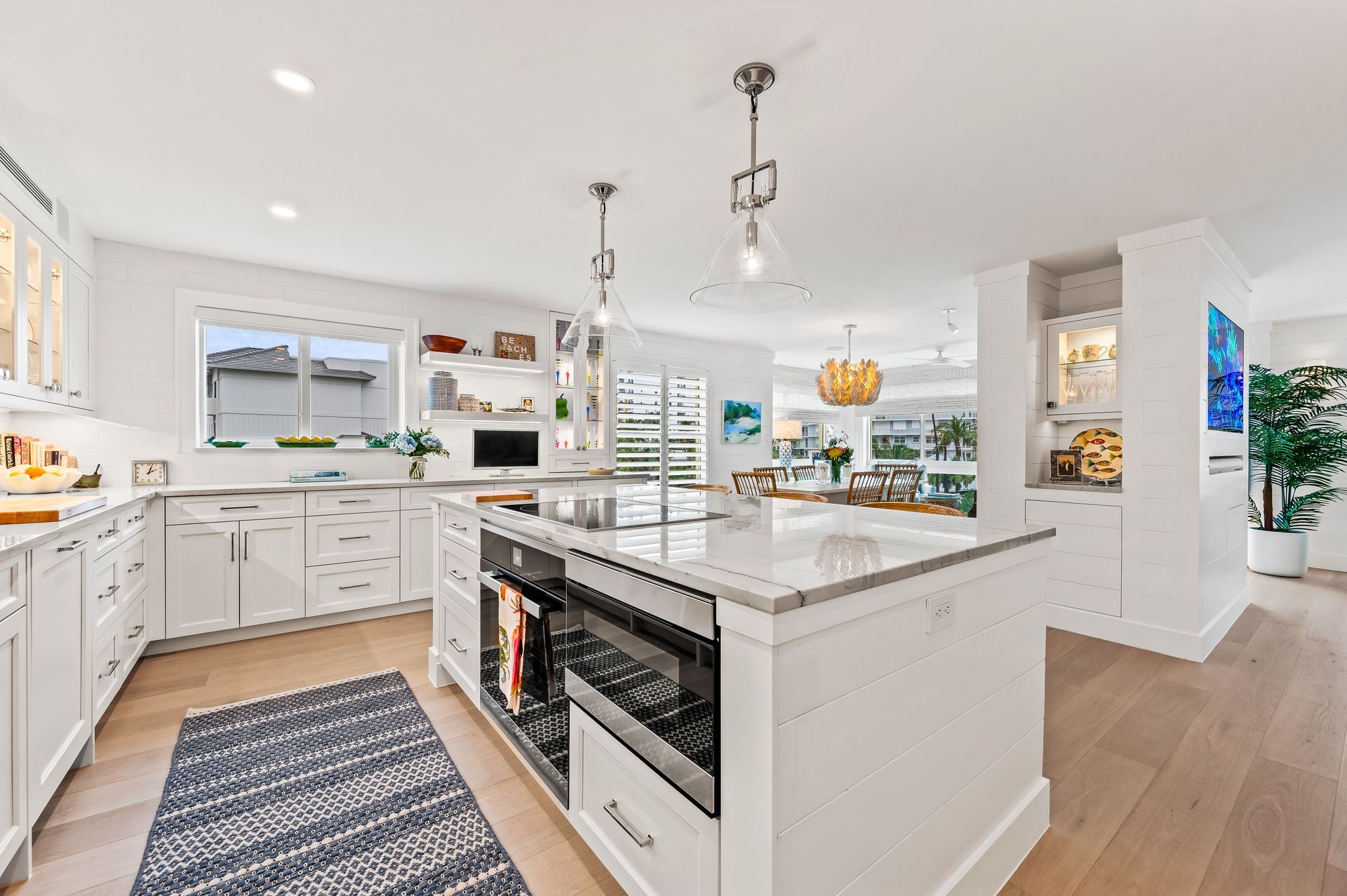 A kitchen with white cabinets and stainless steel appliances and a large island.