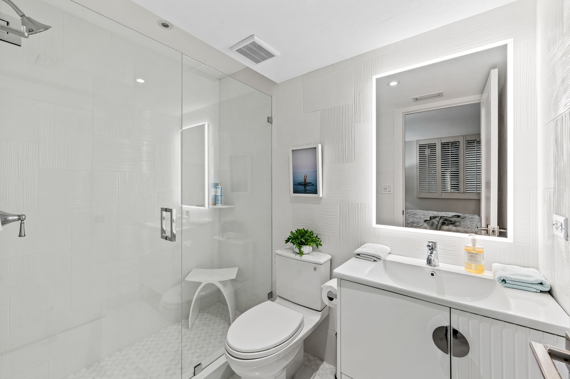 A bathroom with a toilet , sink , shower and mirror.