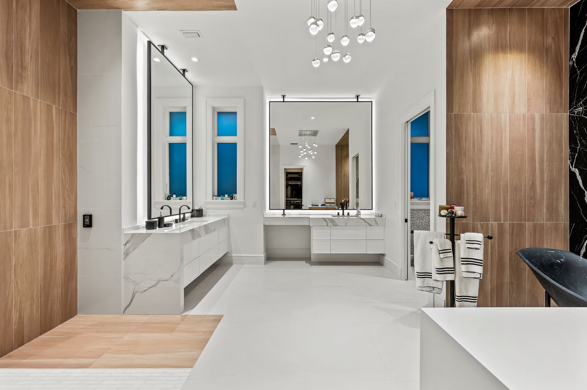 A bathroom with two sinks , a tub , and a large mirror.