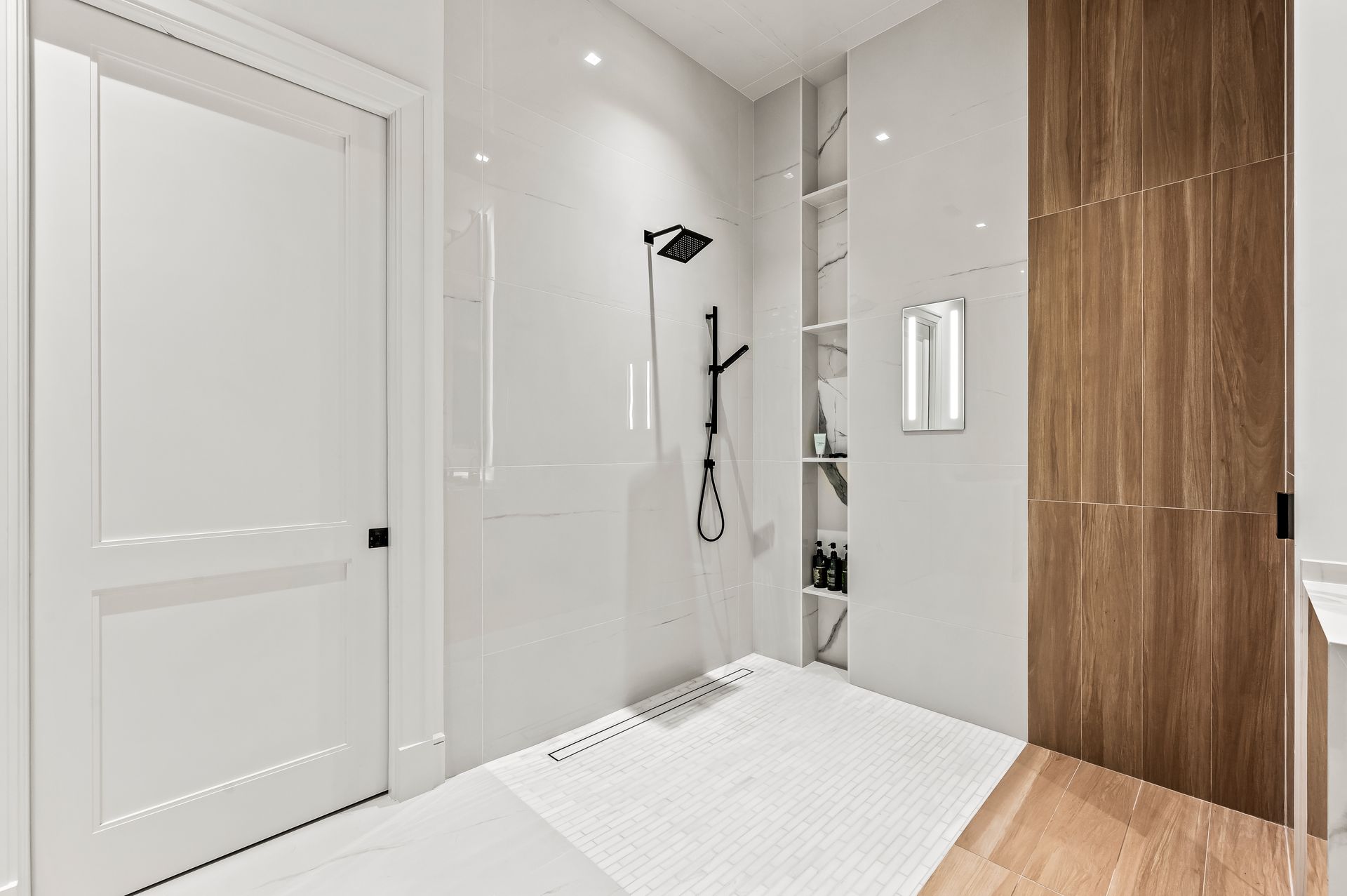 A bathroom with a walk in shower and a wooden door.