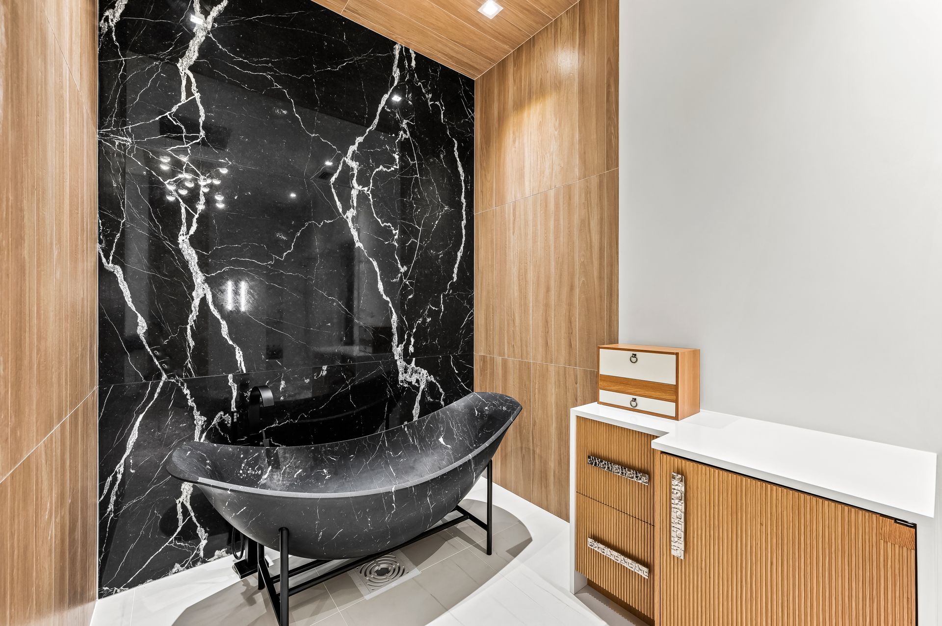 A bathroom with a black and white marble wall and a black bathtub.