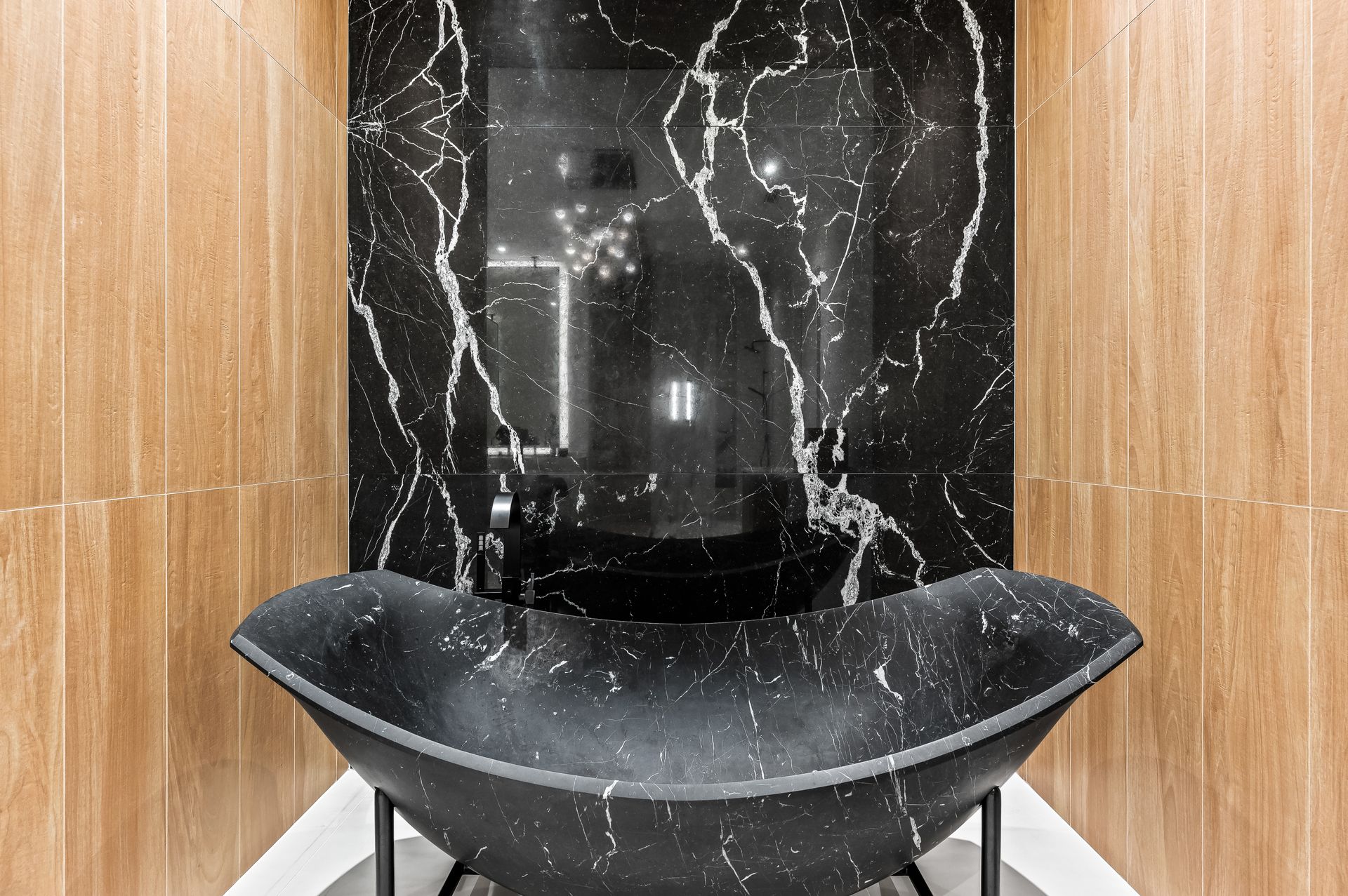 A bathroom with a black marble sink and a black marble wall.