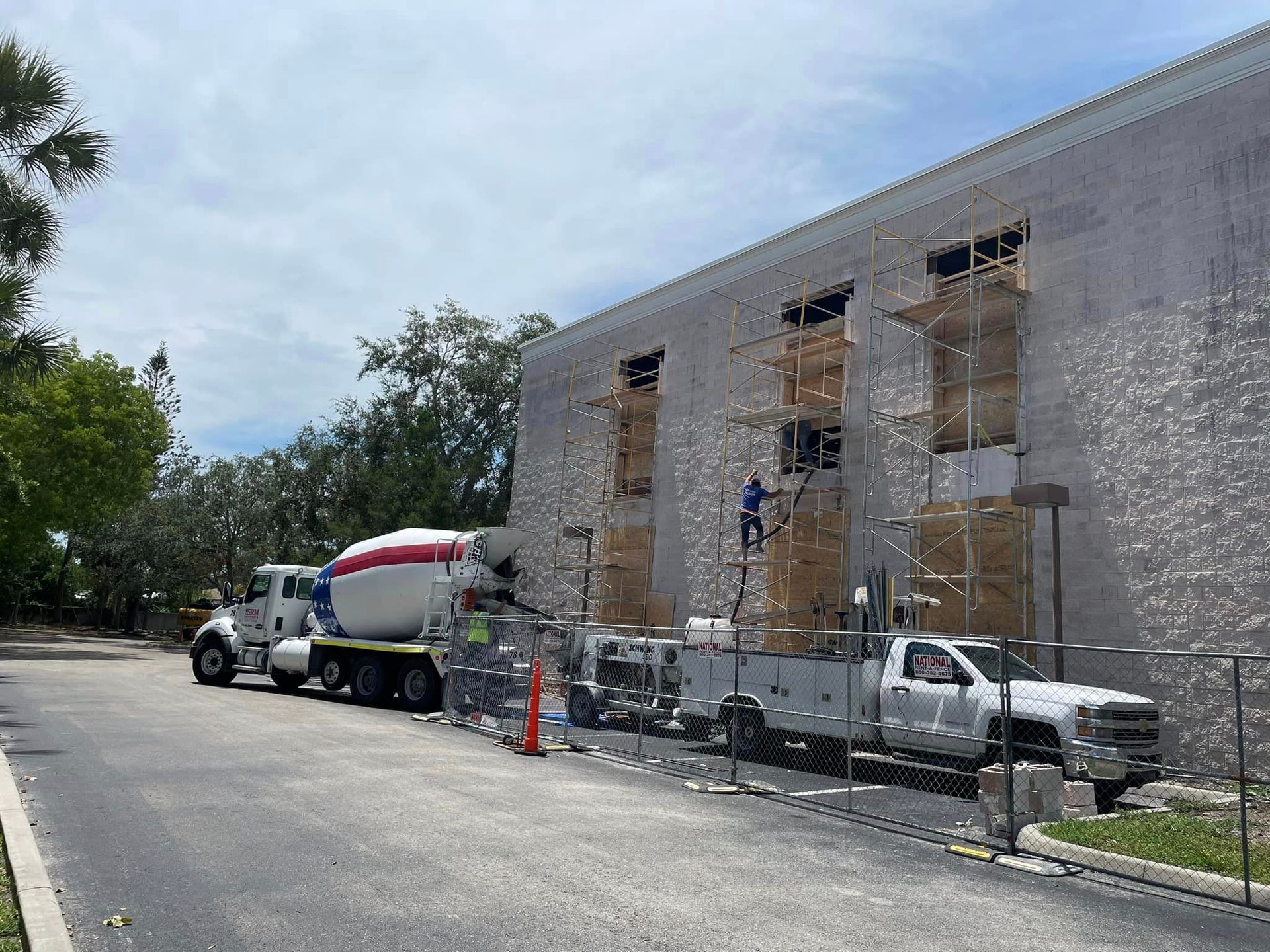 A concrete mixer truck is parked in front of a building under construction.