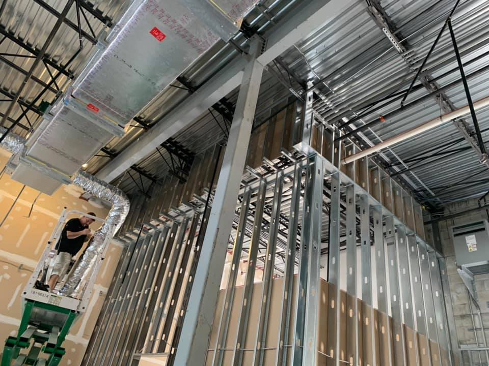 A man is standing on a ladder in a building under construction.