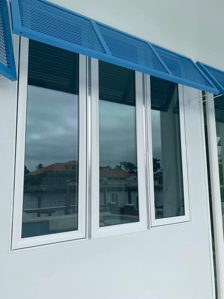 A white window with a blue awning over it.