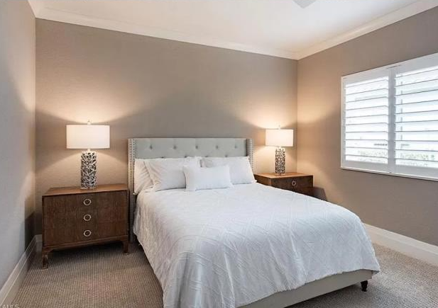 A bedroom with a bed , nightstands , lamps and a window.