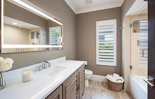 A bathroom with two sinks , a toilet , and a large mirror.