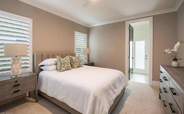 A bedroom with a bed , nightstand , dresser and two windows.