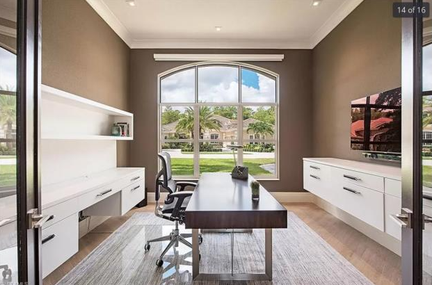 A home office with a desk , chair and television.