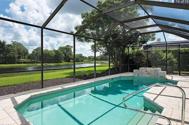 A swimming pool with a screened in area and a view of a lake.