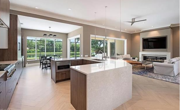 A kitchen and living room in a house with a large island in the middle.