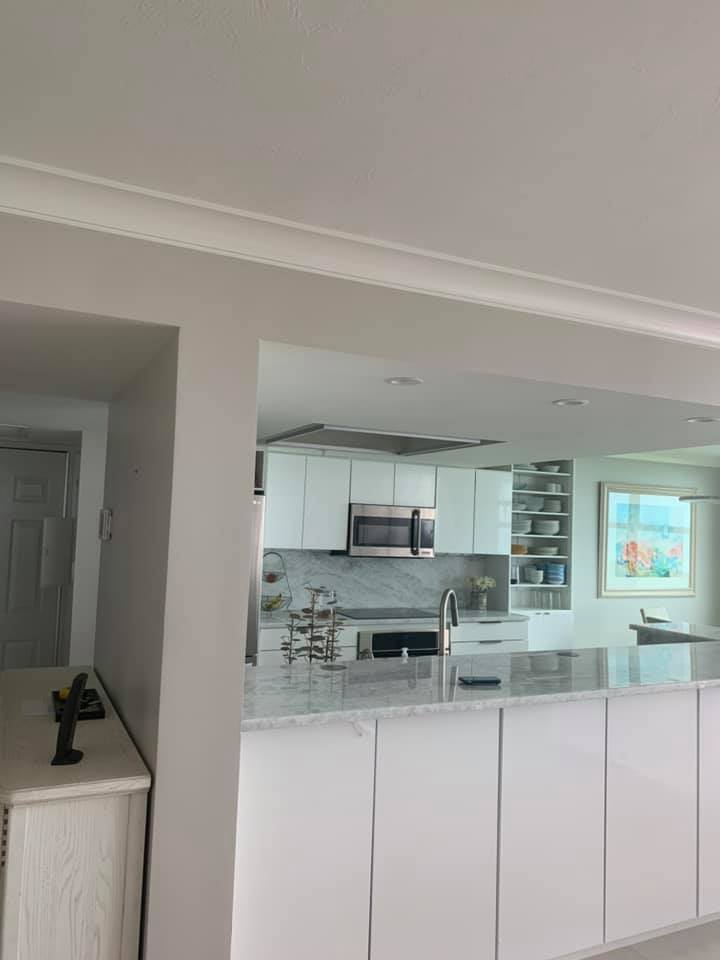 A kitchen with white cabinets , stainless steel appliances , and a large island.