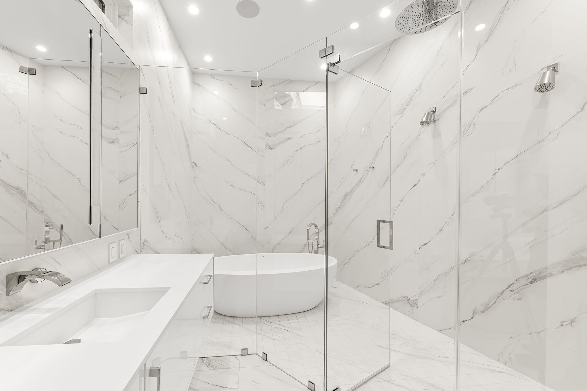 Luxurious white marble bathroom with glass shower and soaking tub.