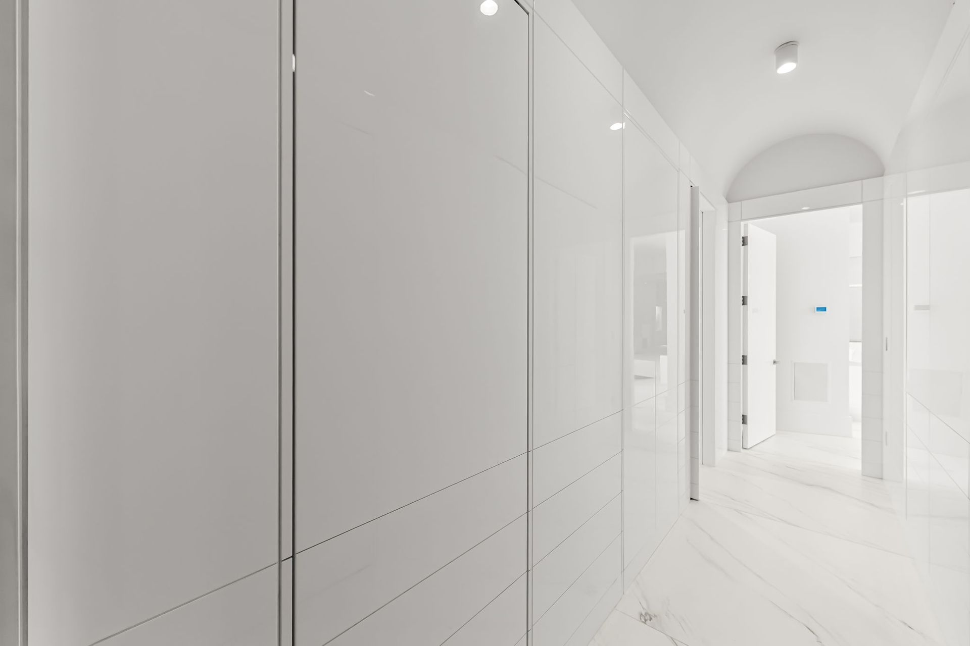 White hallway with glossy closet doors on the left and doorways on the right.