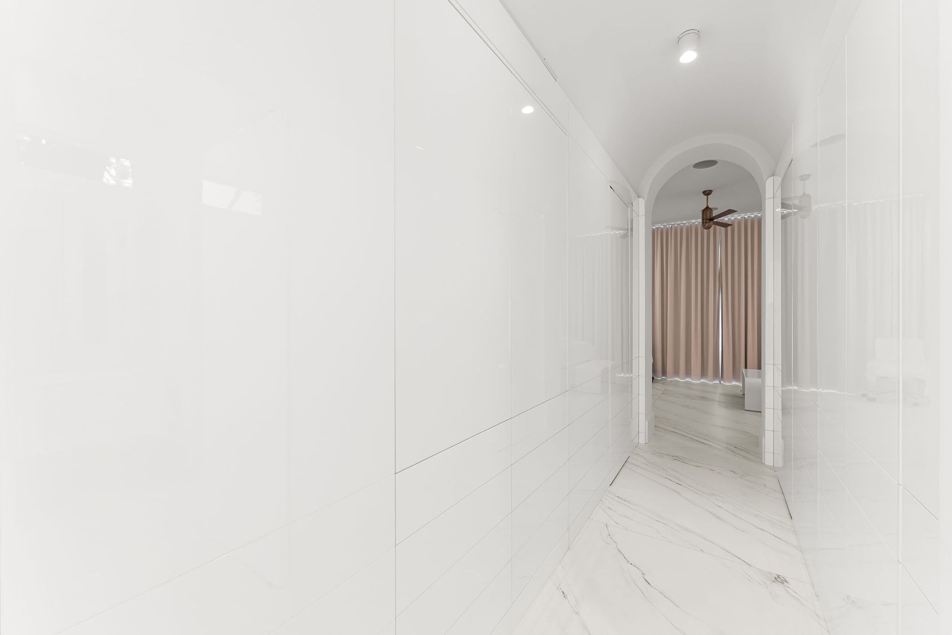 White hallway with curved ceiling, leading to a room with curtains.
