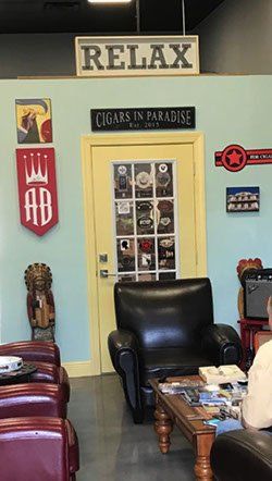 A man is sitting in a chair in a room with a sign that says relax.