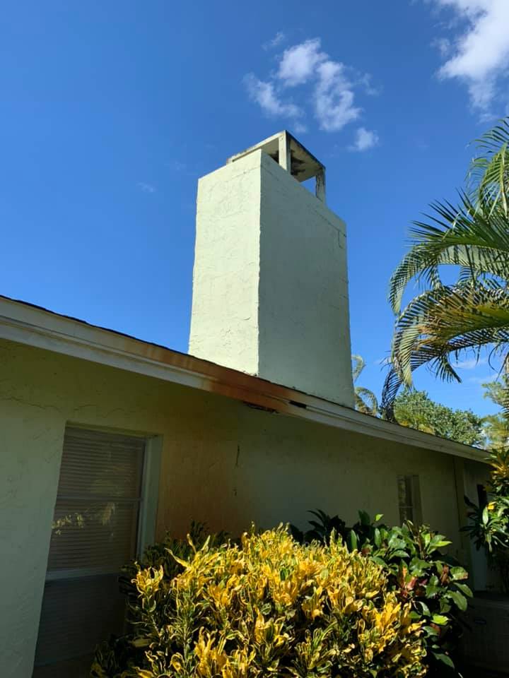 A white house with a chimney on the side of it.