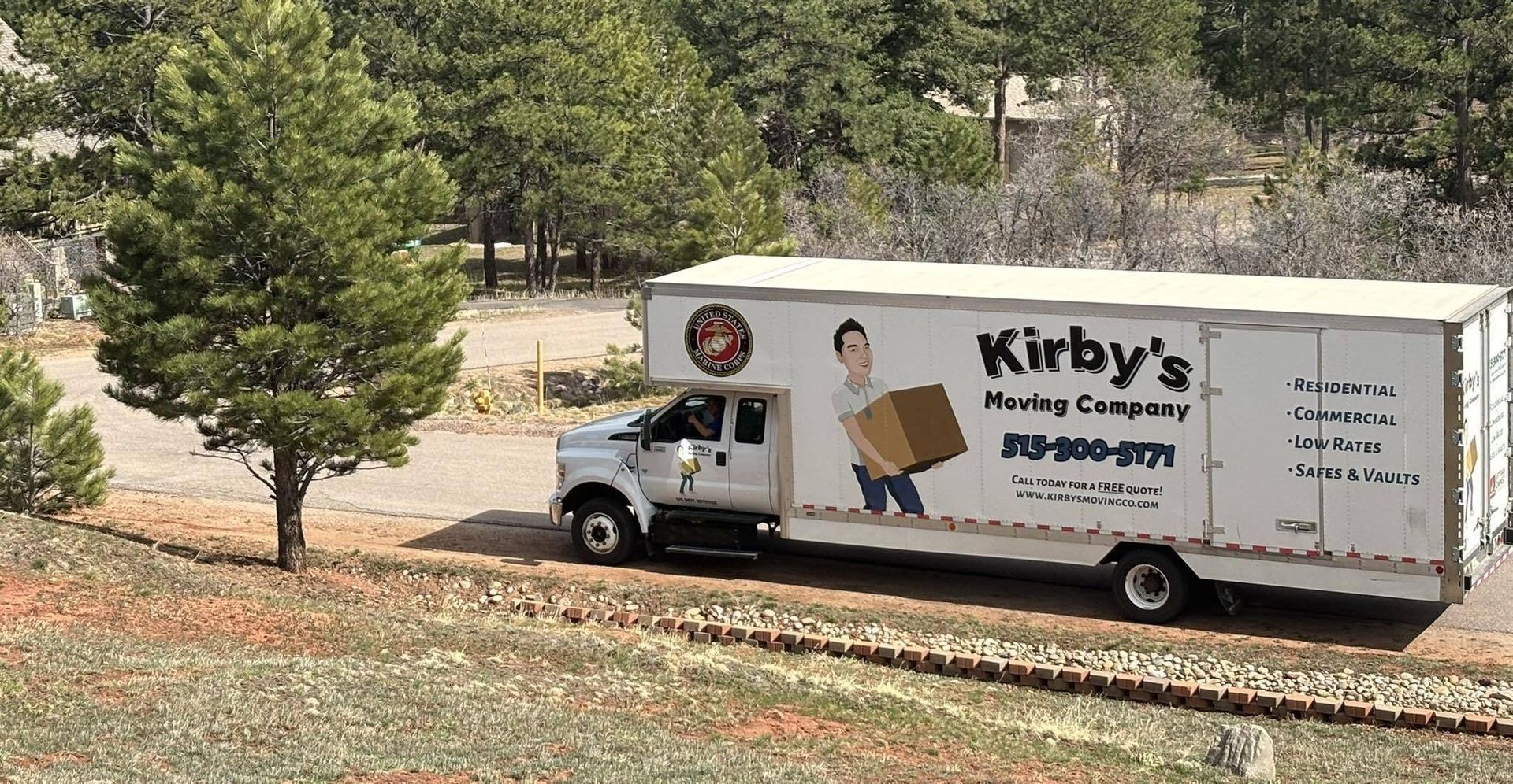 Kirby’s Moving Company truck parked on a grassy slope near trees and a house