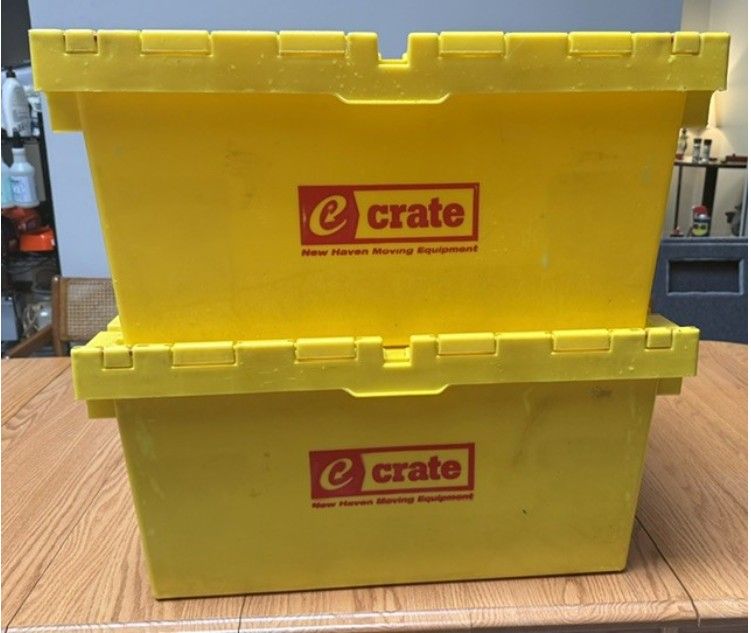 Two stacked yellow eCrate plastic storage bins on a wooden table