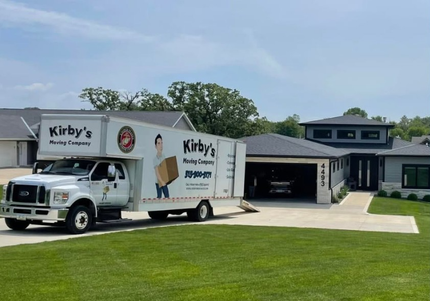 Two movers unloading cardboard boxes from a white moving truck onto a sidewalk