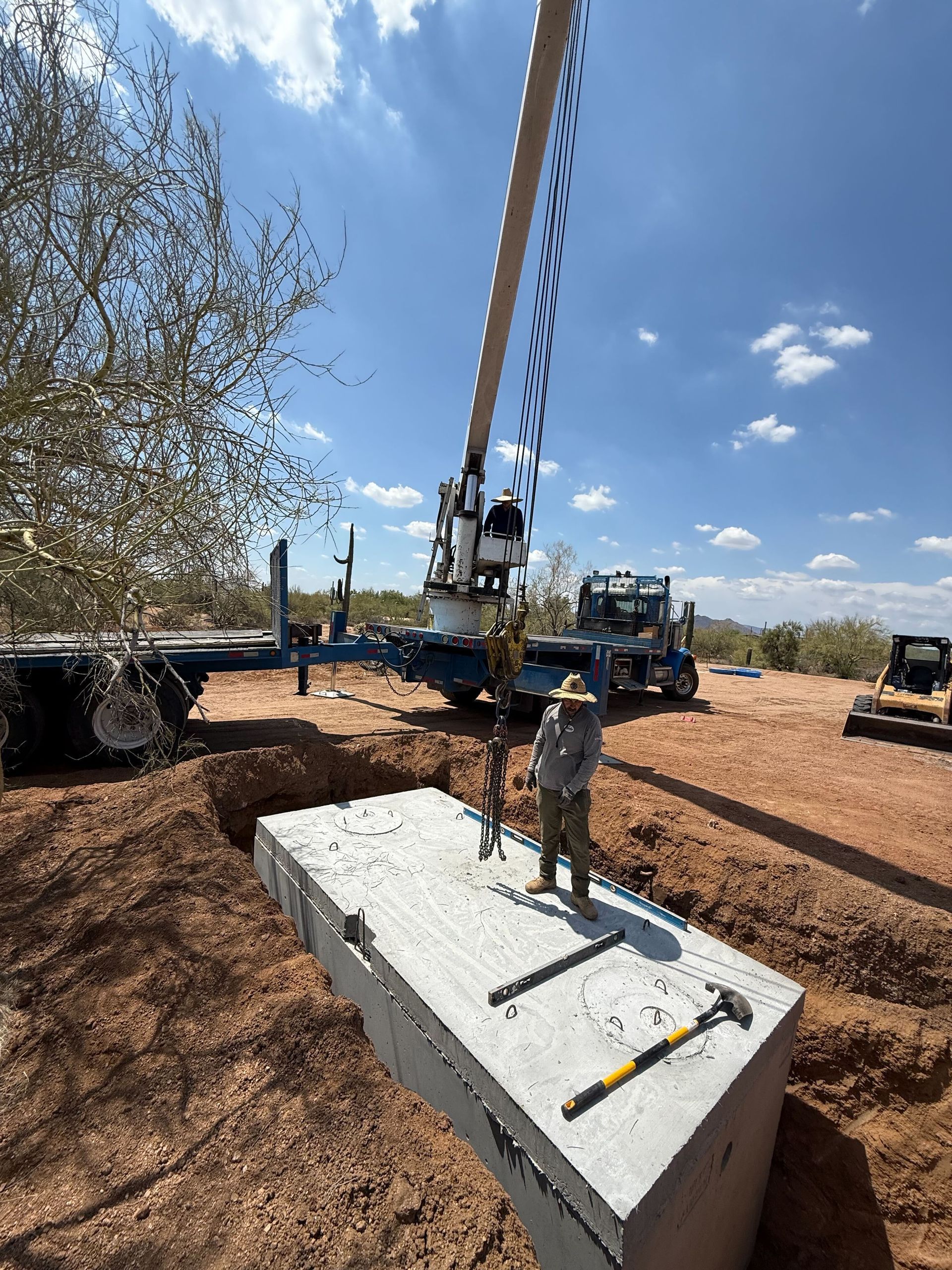 Construction workers guide a concrete crane pour at a site under a blue sky.