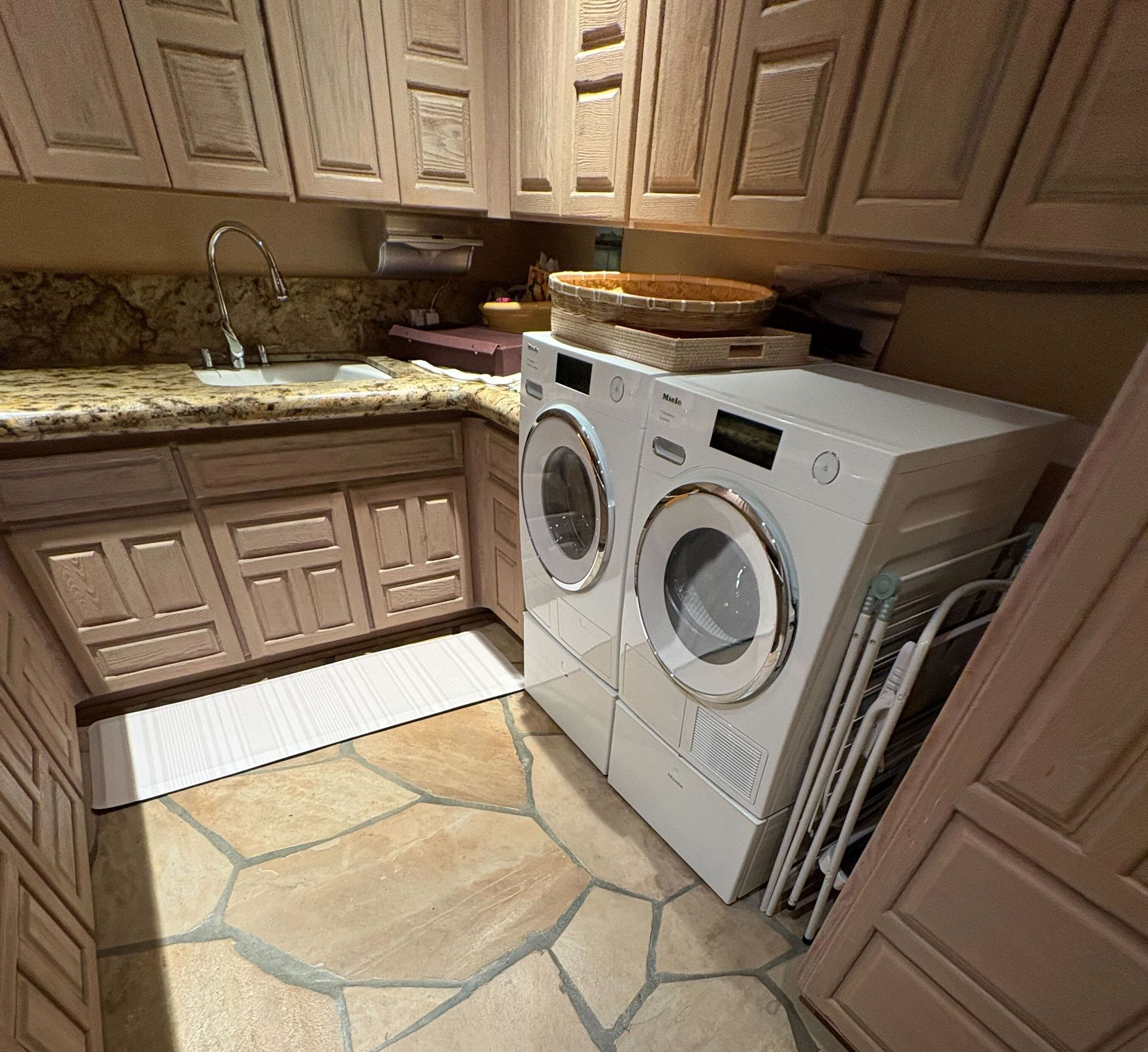 Laundry room with beige cabinets, granite counter, and a white washer and dryer on a tiled floor