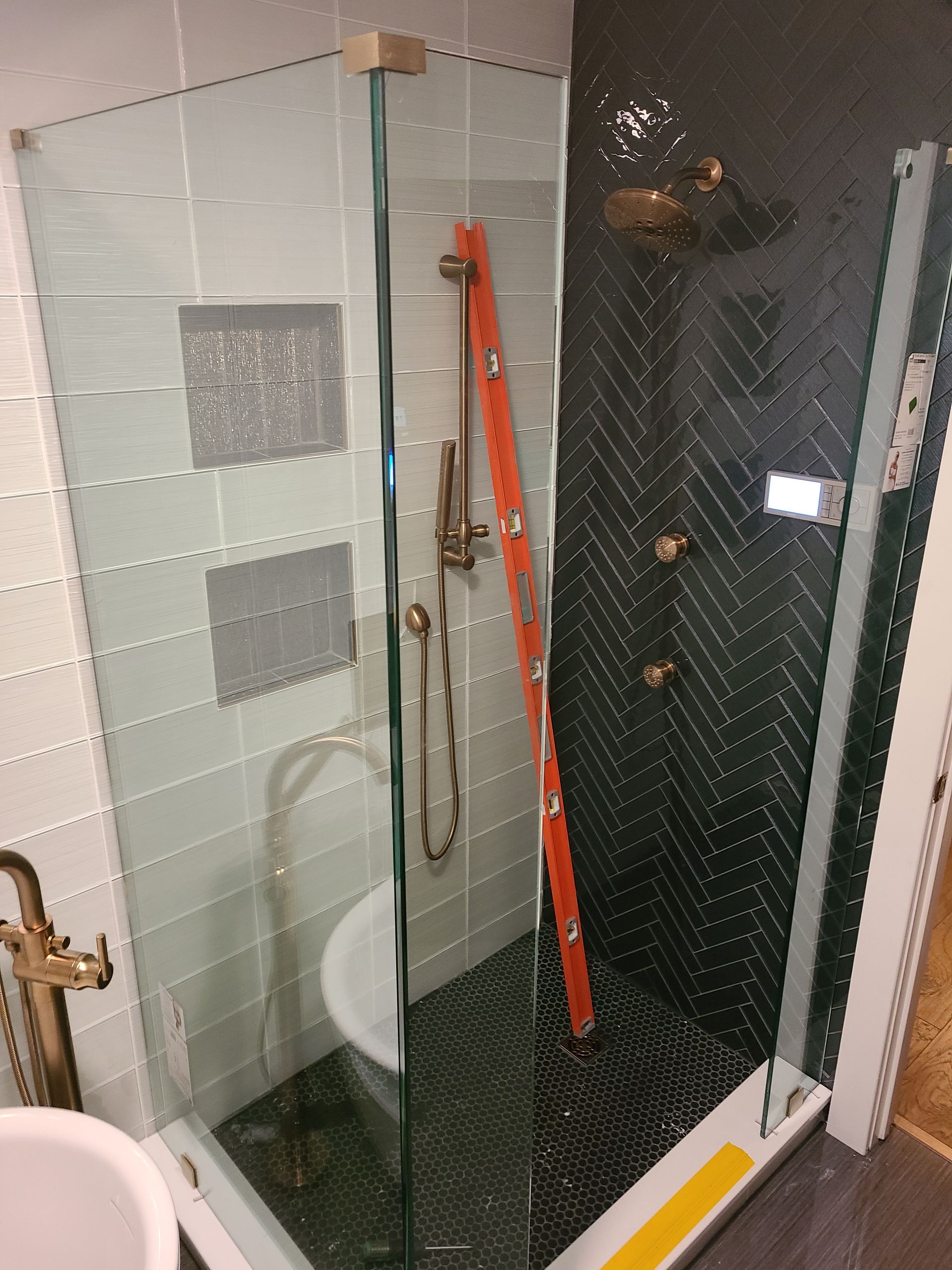 Shower enclosure with glass panels, level against the glass, tile walls.