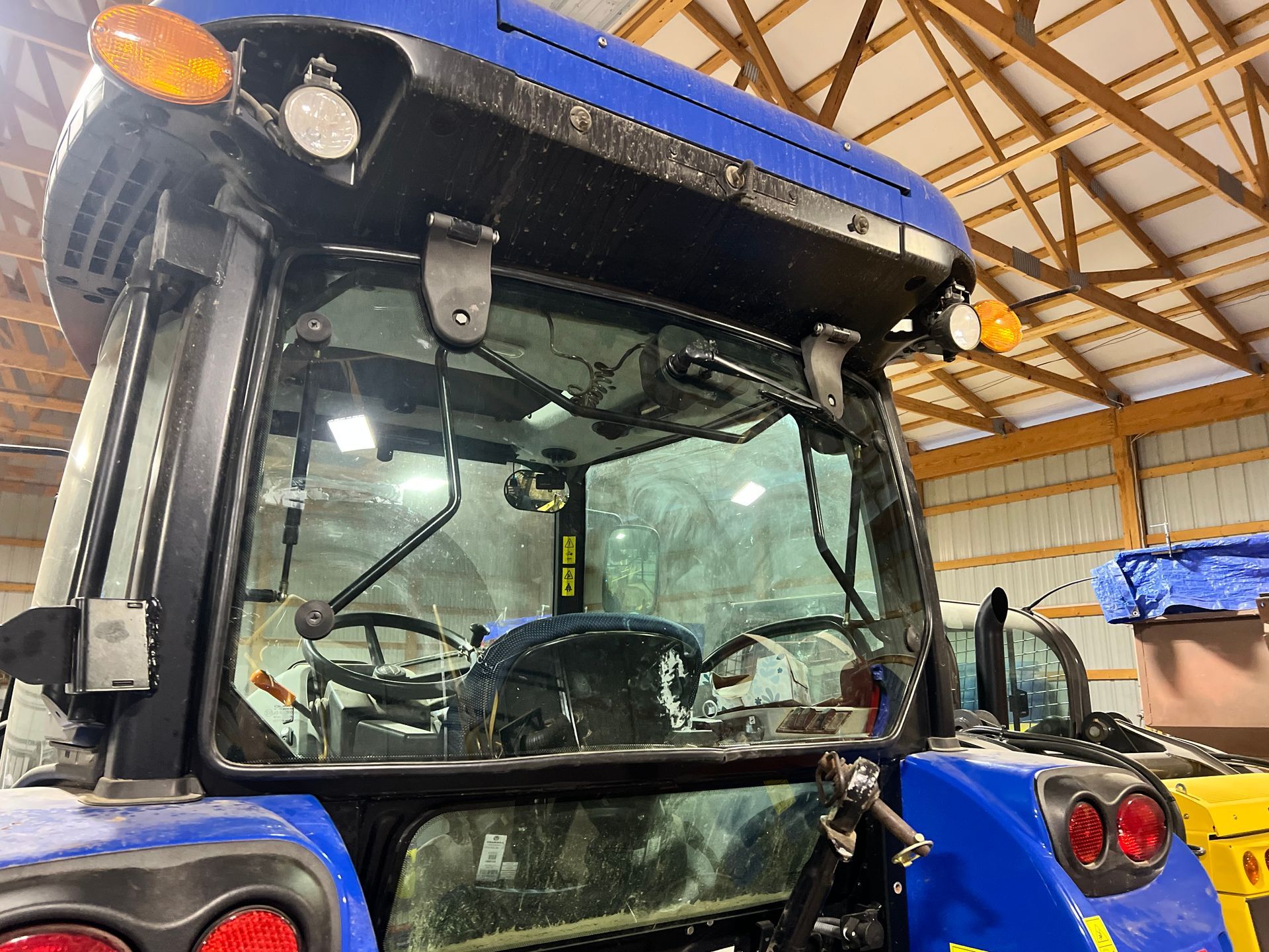 Blue tractor cab with windshield, lights, and interior visible.
