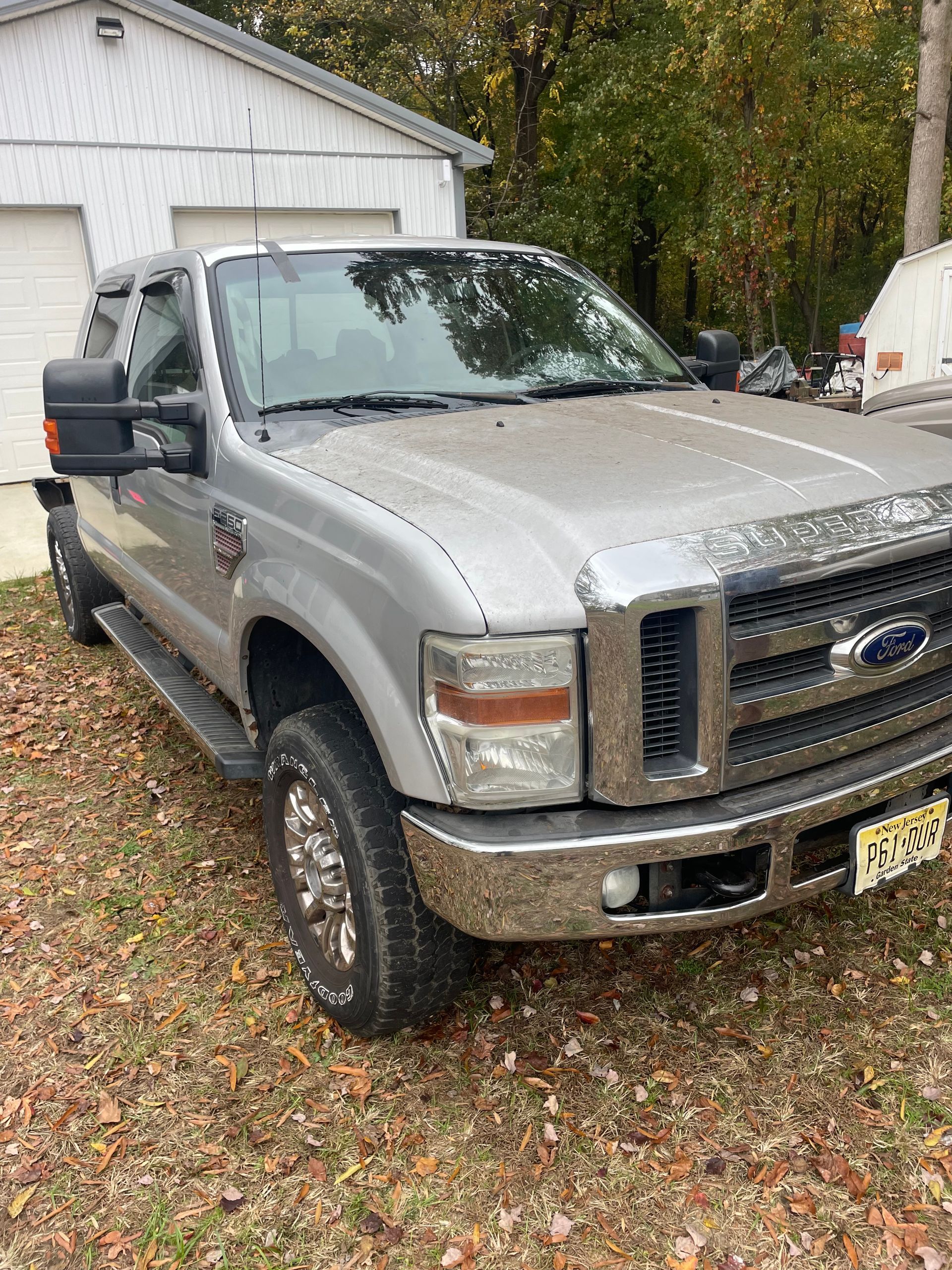 Silver Ford pickup truck parked in front of a white garage.