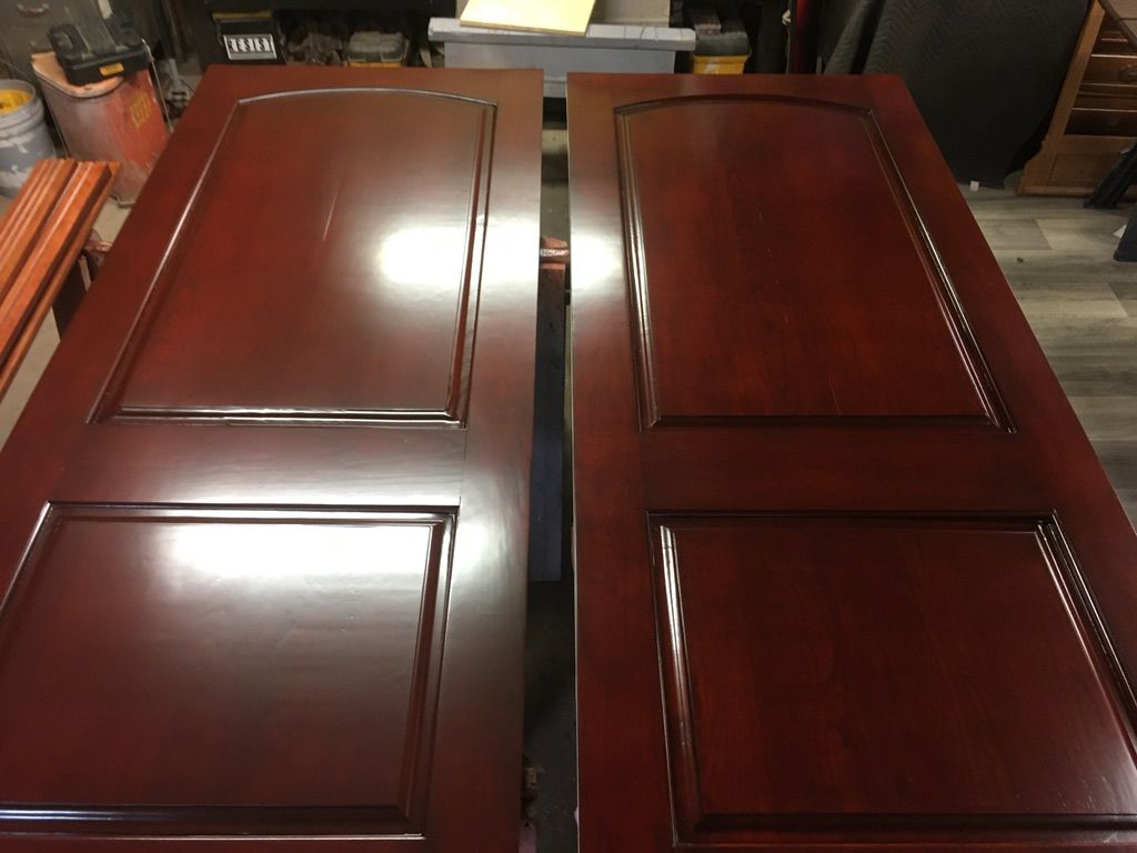 Two stained reddish-brown wooden doors, lying side-by-side, indoors.